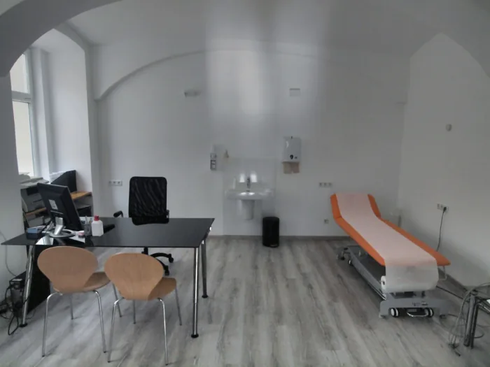 Behandlungsraum mit Schreibtisch und Untersuchungsliege